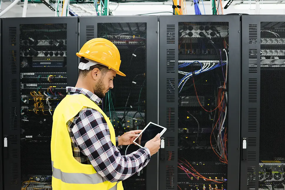 Young technician working with tablet inside a data center room.